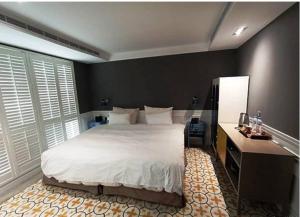 a bedroom with a large white bed and a desk at 朵兒dor韓國汗蒸幕 동대문점 商務旅店 in Taipei
