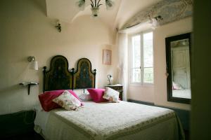 Un dormitorio con una cama con almohadas rosas y una ventana en B&B Le Gemme, en Dolceacqua