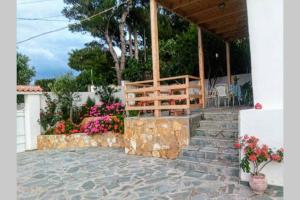 eine Veranda eines Hauses mit Blumen und einem Zaun in der Unterkunft MAGIK HOME RELAXATION in Kalívia Thorikoú