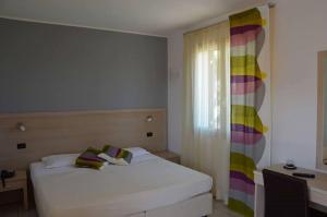 a bedroom with a white bed and a window at Hotel Bulla Regia in Fontane Bianche