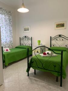 2 letti in una camera con lenzuola verdi di Casa Vacanze Ileana a Patti