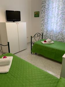 Cette chambre comprend 2 lits avec des draps verts et une télévision. dans l'établissement Casa Vacanze Ileana, à Patti