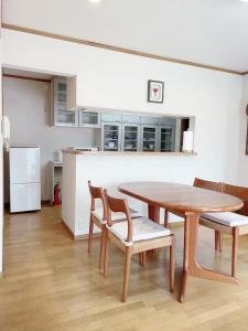 a kitchen with a wooden table and chairs and a kitchen with a refrigerator at Young House in Matsudo