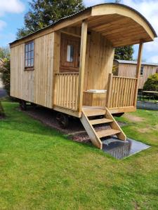 a large wooden cabin with a porch and stairs in a yard at Lucker mill shepherds huts in Lucker