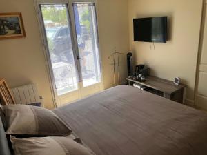 una camera da letto con un letto, una scrivania e una televisione di La Pépinière a Saint-Sulpice-et-Cameyrac