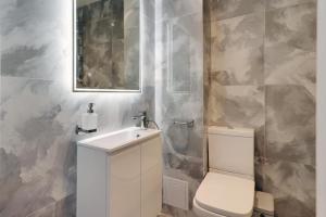 een badkamer met een toilet, een wastafel en een spiegel bij Master accommodation suite 7 sea view in Hastings