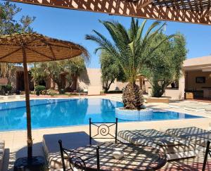 - une piscine avec une table, des chaises et un parasol dans l'établissement La Maison Des Oliviers, à Marrakech