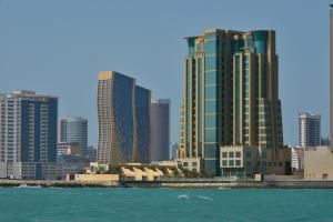 um horizonte da cidade com edifícios altos e a água em Grand Swiss-Belhotel Waterfront Seef em Manama