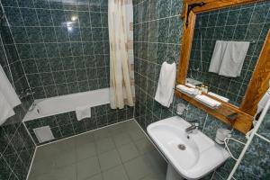 Baño de azulejos verdes con lavabo y bañera en Yuzhny Dvorik, en Leninskiye Gorki