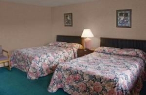 a hotel room with two beds and a lamp at Best Inn in Wellsville