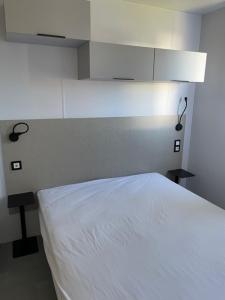 a bedroom with a white bed and a white cabinet at Camping Oasis Louisiane Grand Large III in Ostend