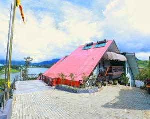 un edificio con techo rojo junto a una masa de agua en Lake View Holiday Resort en Nuwara Eliya