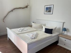 a white bed with white sheets and pillows on it at Pension Villa Frohsinn Sellin auf Rügen in Ostseebad Sellin