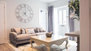 uma sala de estar com um sofá, uma mesa e um relógio em Modern Apartment with FREE Parking, WIFI and Netflix em Stratford-upon-Avon