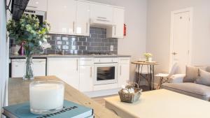 a kitchen with white cabinets and a table with a glass of milk at Modern Apartment with FREE Parking, WIFI and Netflix in Stratford-upon-Avon