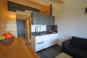 - une cuisine avec des placards blancs, une table et un canapé dans l'établissement Studio LUMINEUX à 5 minutes du lac de Serre Ponçon, à Prunières