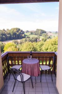 a table with two chairs and a bottle of wine on a balcony at Ferienwohnungen Soravia in Gamlitz
