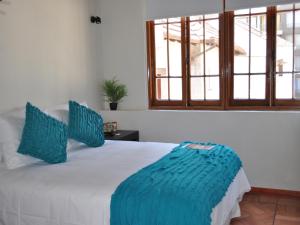 a bedroom with a white bed with blue pillows at Hotel CasaDeTodos in Santiago