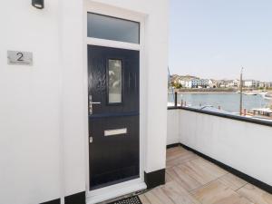 a black door on a balcony with a view of the water at 2 Beach Cottage in Plymouth