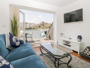 a living room with a blue couch and a glass table at 2 Beach Cottage in Plymouth