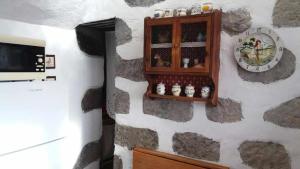 a wall with a clock and a shelf with bottles at Casa Rural Las Cáscaras Tejeda Gran Canaria in Tejeda