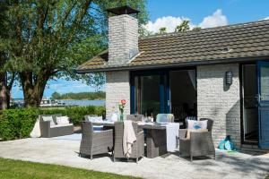 a patio with a table and chairs and a building at Holiday home- Bungalow in Loosdrecht