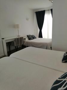 a hotel room with two beds and a window at Hotel Llorca in Platja de l’Almadrava