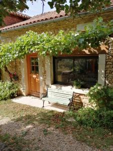 un banco frente a una casa con ventana en En plein air en Coursac