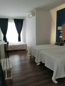 a hotel room with two beds and a window at Hotel Llorca in Platja de l’Almadrava
