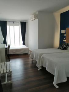 una camera d'albergo con due letti e una finestra di Hotel Llorca a Platja de l’Almadrava