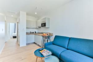 a living room with a blue couch and a kitchen at VILLA14 in Dijon