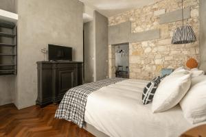 ein Schlafzimmer mit einem Bett und einer Steinmauer in der Unterkunft Suite San Tommaso - Ortigia Holidays in Syrakus