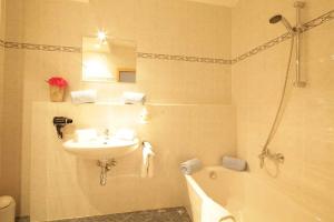 La salle de bains est pourvue d'un lavabo, de toilettes et d'une baignoire. dans l'établissement Aparthotel Alpenpark, à Kochel am See