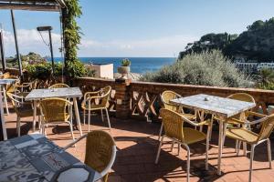 a patio with tables and chairs and the ocean at Hotel Villino Gallodoro in Taormina