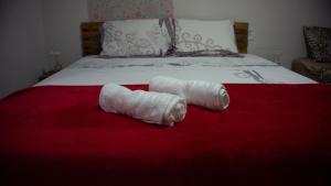 - 2 serviettes enroulées sur une couverture rouge sur un lit dans l'établissement Pousada Viana, à Garanhuns