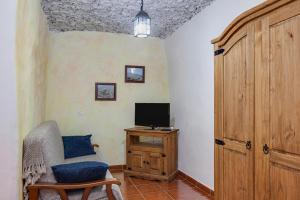 een kamer met een tv, een stoel en een deur bij Casa Chinamada in La Laguna