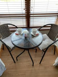 een glazen tafel met twee stoelen en twee bekers erop bij Sliabh Amharc in Laragh