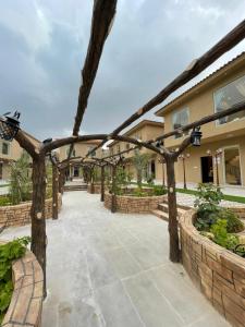 a patio with a wooden pergola in front of a house at REVERA RESORT in Al Barkah