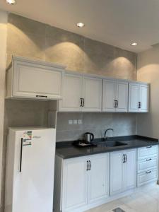 a kitchen with white cabinets and a refrigerator at REVERA RESORT in Al Barkah
