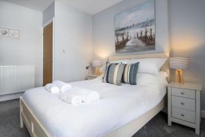 a bedroom with a large white bed with towels on it at Abbey Road Boutique Holiday Apartment in Llandudno