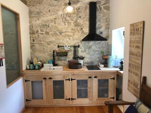a kitchen with a sink and a stone wall at Casa das Raposas in Zambujal