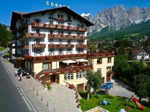 un hotel en las montañas con coches estacionados frente a él en Hotel Corona, en Cortina dʼAmpezzo