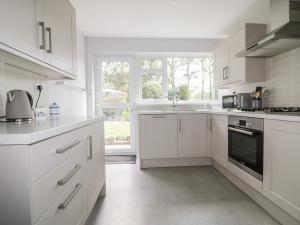 a white kitchen with white cabinets and a window at Sea Salt in Bude