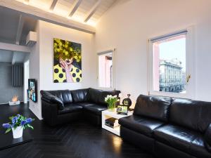 a living room with a black leather couch at OBERDAN SUITE Appartamento nel cuore di Bologna in Bologna