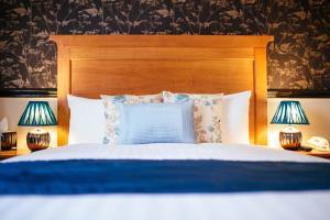 uma cama com uma cabeceira de madeira e 2 candeeiros em Pymgate Lodge Hotel Manchester Airport em Cheadle