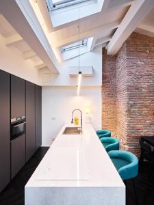 a kitchen with a large white counter and blue chairs at OBERDAN SUITE Appartamento nel cuore di Bologna in Bologna