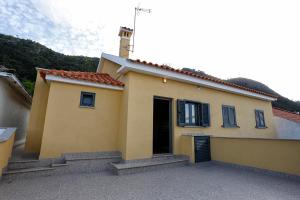 una pequeña casa amarilla con puerta y escaleras en Douro House, en Tabuaço