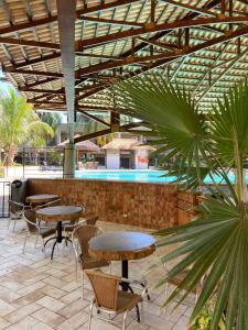 a patio with tables and chairs and a swimming pool at Hotel OT in Três Lagoas