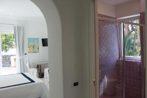 um quarto com uma cama e uma cabina de duche em vidro em Villa Marinella em Ischia