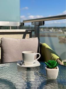 a cup of coffee sitting on a table with a plant at Lake and Spa Apartman in Velence